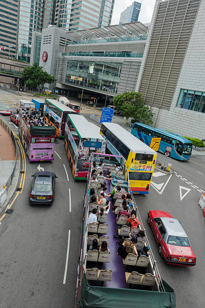 Hong Kong, China - May 3rd, 2014: Tourists on open-top sightseeing buses, Hong Kong Island, China. Apple store in the background, near 2IFC Tower.
