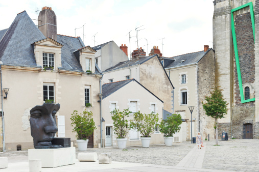 Angers, France - July 28, 2014: woman and statue on Rue du Musee street in Angers, France. Angers is city in western France and it is the historical capital of the province of Anjou