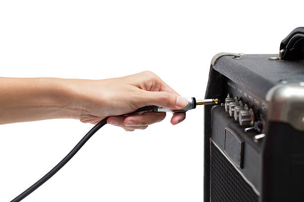 woman hand plugging into the amplifier guitar on white backgroun woman hand plugging into the amplifier guitar on white background amplifier plug stock pictures, royalty-free photos & images