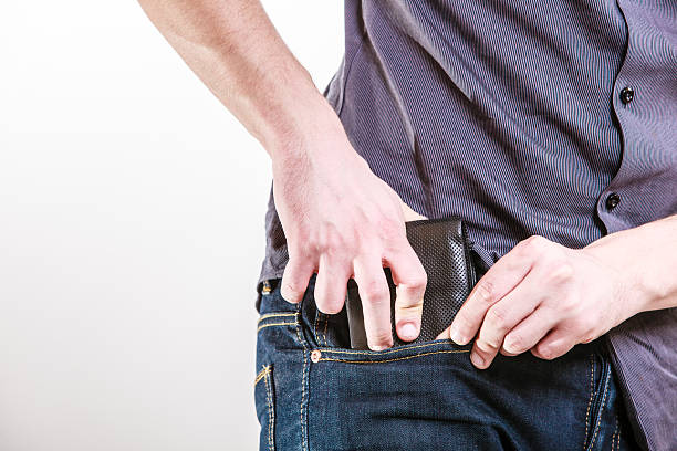 Closeup. Careless man putting wallet in his pocket. Theft. Closeup of male hands. Careless man putting the wallet in his pocket. Risk of theft. Isolated on white. Studio shot. leather pocket clothing hide stock pictures, royalty-free photos & images