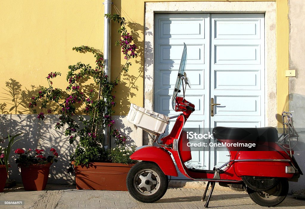 scooter rojo viejo estilo italiano cerca de una puerta - Foto de stock de Ciclomotor de pedales libre de derechos
