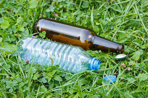 istock Plastic and glass bottle with bottle caps on grass 506468502