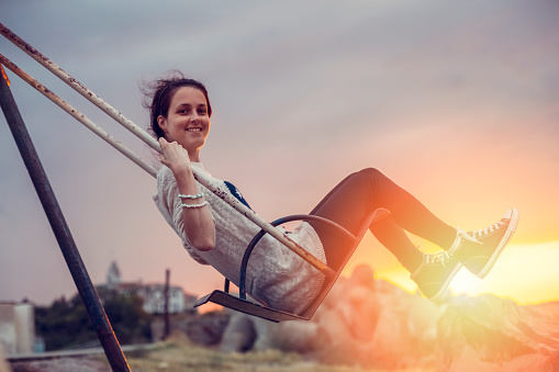 Happy girl swinging on sunset