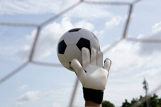 istock goalkeeper's hands reaching foot ball 506471811