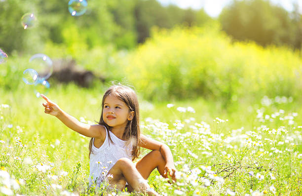 Little girl having fun in summer day, soap bubbles