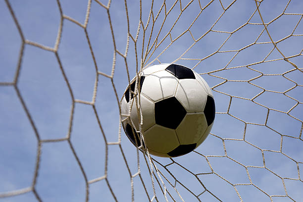 istock foot ball in the goal net 506472389