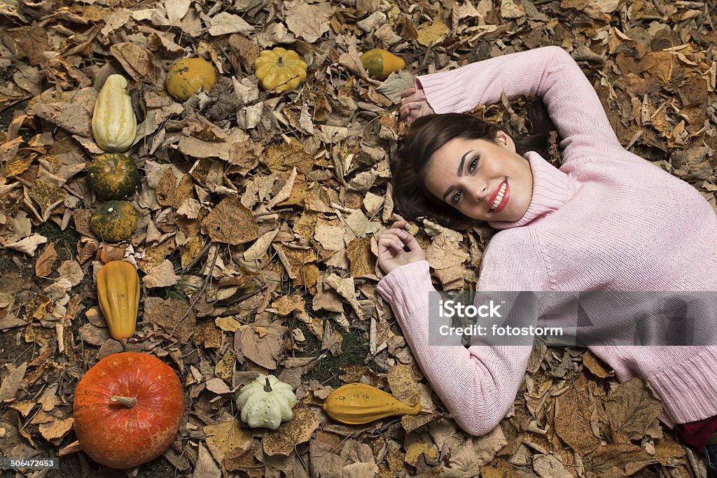 Young woman lying down on autumn leaves Young woman lying down on autumn leaves. Adult Stock Photo