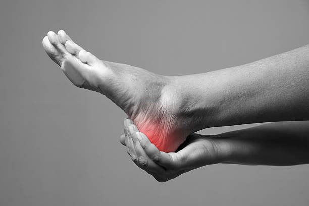 Pain in the foot on a gray background Pain in the foot. Massage of female feet. Pain in the human body on a gray background. Black and white photo with red dot human foot stock pictures, royalty-free photos & images
