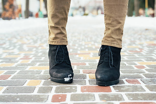 istock Female feet in brown jeans and black winter boots standing 506474792