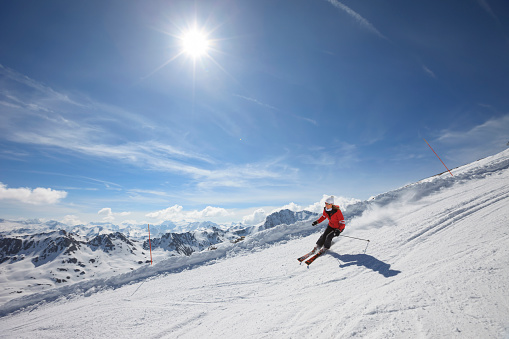 Mid adult women snow skier skiing, enjoying on sunny ski resorts. Skiing carving at high speed.