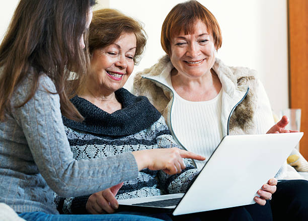istock Smiling female pensioners and relative browsing web on laptop 506480046