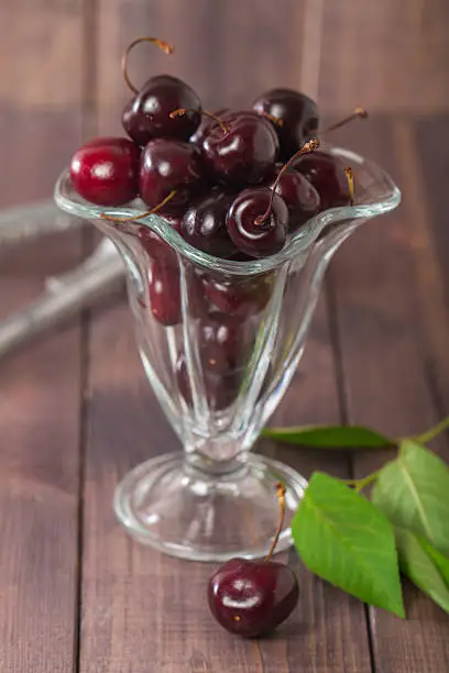 Fresh sweet cherry in a glass bowl on dark wooden background