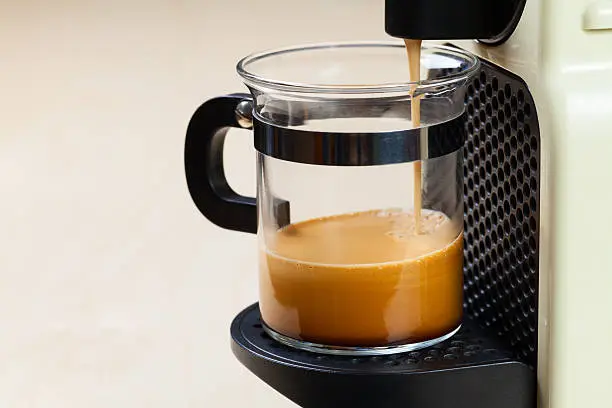 Single-serving coffee machine dispenses  espresso in a glass cup