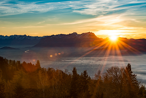 Sunset over the misty rhine valley. It's the borderland between austria and switzerland with the river rhine in the middle and the swiss mountains in the background.