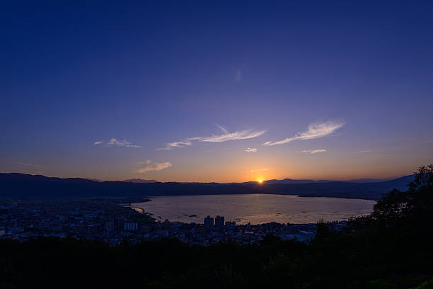 The city of Suwa at the moment of sunset The city of Suwa at dusk. The Suwa region is the leading industrial area of Nagano and was once known as "The Oriental Switzerland" for its highly developed precision machinery industry. suwa lake photos stock pictures, royalty-free photos & images