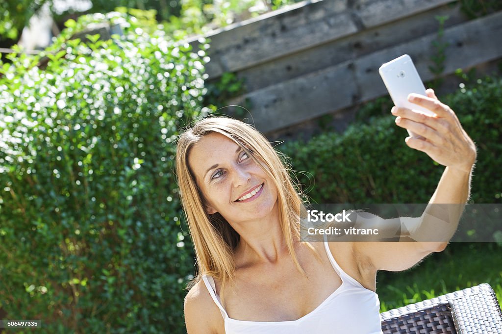 Beautiful young Woman Taking Selfie in the Park Attractive young woman with curly hair taking selfie on a bench in the city park 30-39 Years Stock Photo