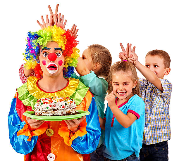 children with clown blowing candles on cake during birthday
