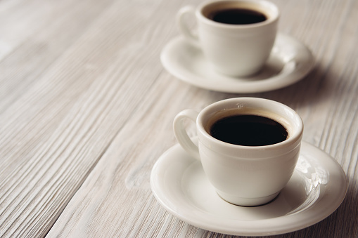 Two cups of coffee on a white wooden table