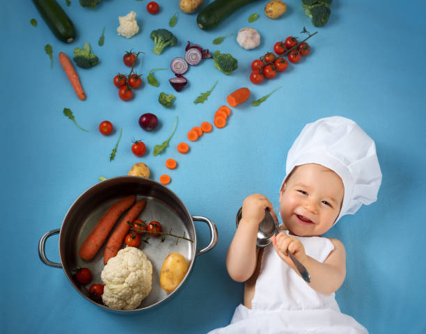istock Baby boy in chef hat with cooking pan and vegetables 506509202