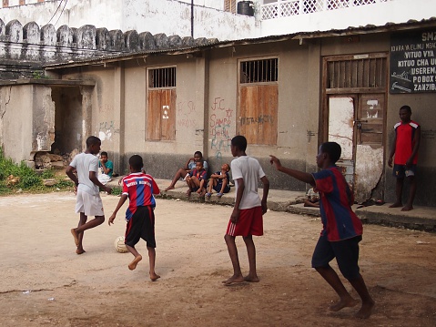 Stone Town, Zanzibar, Tanzania - November 25, 2015: Teenagers playing football in their bare feet in a school yard in Zanzibar's capital, Stone Town.