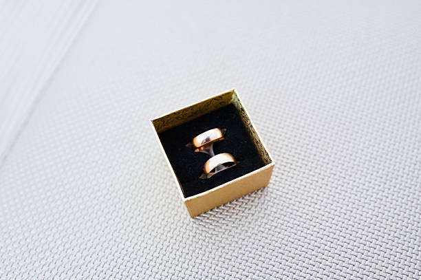 istock Wedding rings on golden box background silver texture 506512150