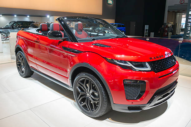 Range Rover Evoque Convertible Brussels, Belgium - Januari 12, 2016: Red Range Rover Evoque Convertible  luxury compact SUV front view. The convertible production model is based on the three-door Evoque Coupe, it includes four seats and a power-retractable soft top roof. The car is on display during the 2016 Brussels Motor Show. The car is displayed on a motor show stand, with lights reflecting off of the body. There are people looking around and other cars on display in the background. evoque stock pictures, royalty-free photos & images