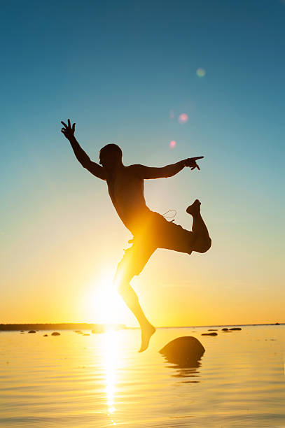 istock Reaching for the Clouds. Funny jumping man silhouette. Sunset background. 506514986