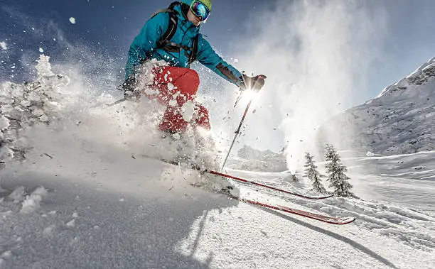 Man freeride skier running downhill on sunny Alps slope.