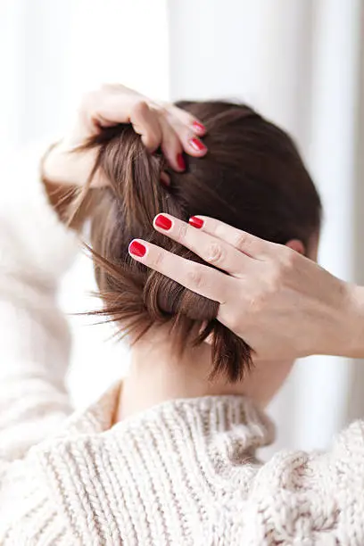 Photo of Woman making hair bun