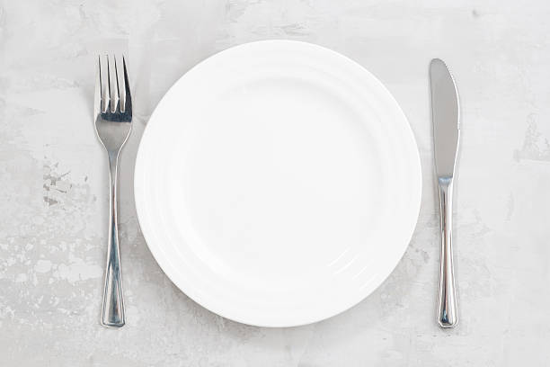 istock concept photo. White empty plate and cutlery, top view 506517558