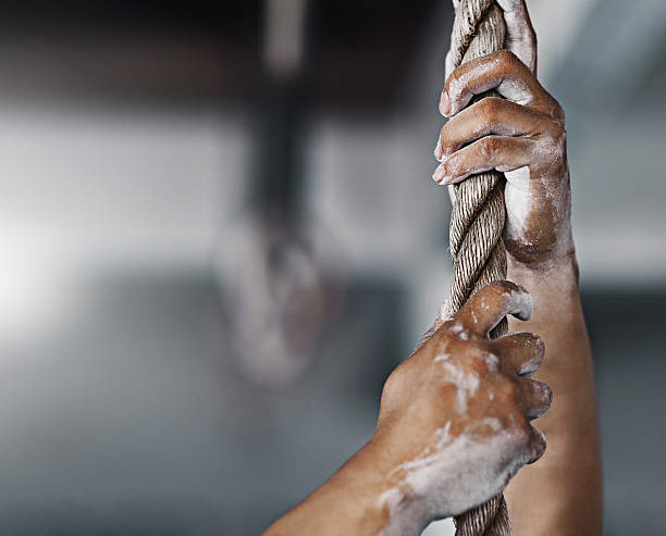 Get a grip! Cropped shot of a young man climbing a rope at the gymhttp://195.154.178.81/DATA/i_collage/pi/shoots/806229.jpg persistence stock pictures, royalty-free photos & images