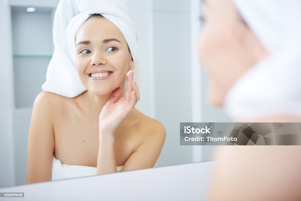 Bella giovane donna applicare idratante viso crema. Cura della pelle concetto - Foto stock royalty-free di Donne