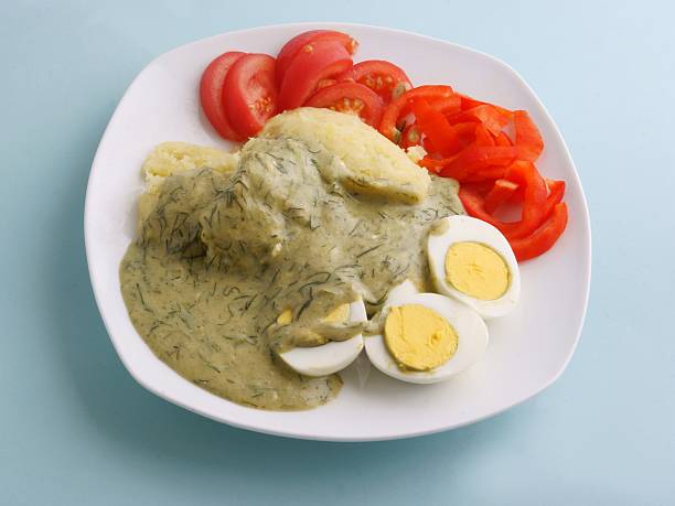 boiled eggs under dill sauce with vegetables for dinner