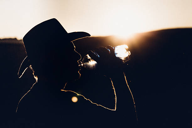 Man drinking a bottle of water, backlit during sunset