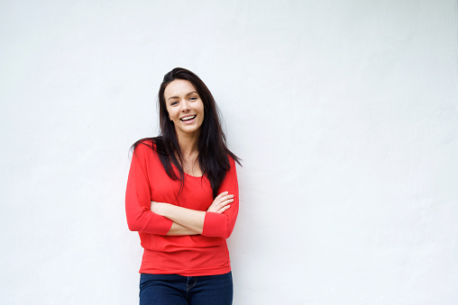 Smiling young woman in red shirt smiling against white background