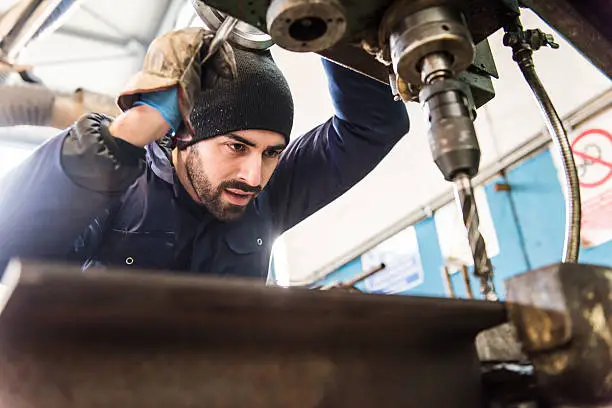 Worker at milling machine in workshop.