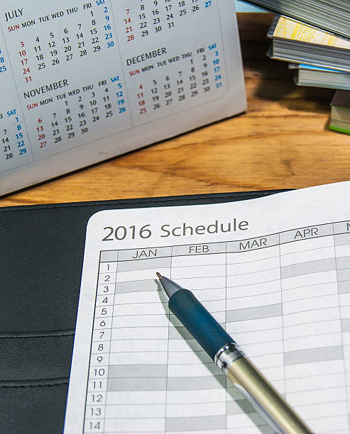 istock pen with open schedule book with calendar on wooden table 506546558