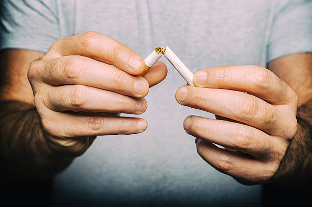istock Quitting smoking - male hand crushing cigarette 506551056