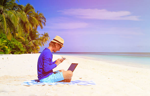 istock man with laptop and mobile phone on tropical beach 506551276