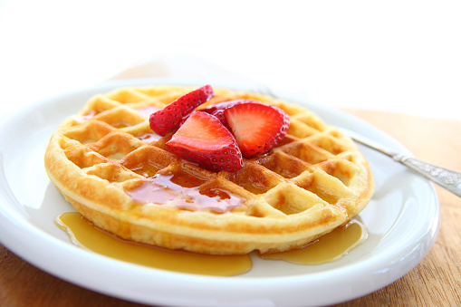 Closeup of waffle with fresh strawberries and syrup with copy space