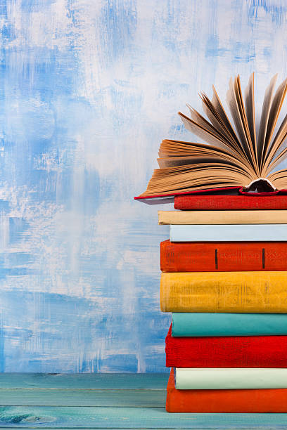 istock Stack of colorful hardback books, open book on blue background 506552164