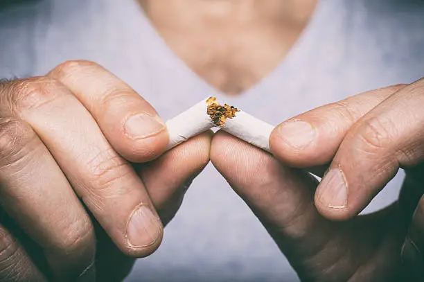 Photo of Quitting smoking - male hand crushing cigarette