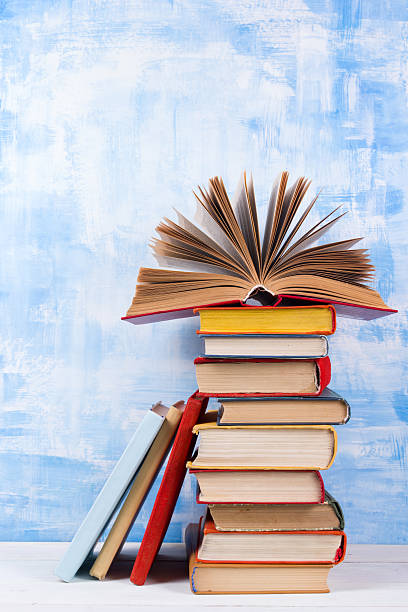 istock Stack of colorful hardback books, open book on blue background 506552318