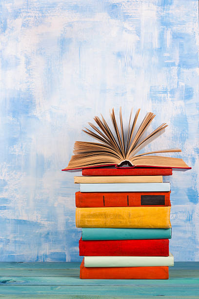 istock Stack of colorful hardback books, open book on blue background 506552374