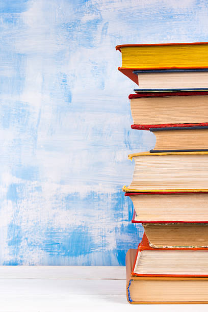 istock Stack of colorful hardback books, open book on blue background 506552412