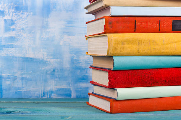 istock Stack of colorful hardback books, open book on blue background 506552602