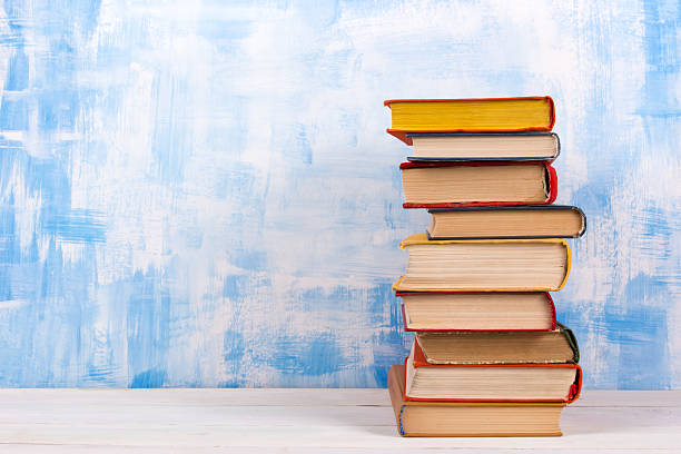 istock Stack of colorful hardback books, open book on blue background 506552730