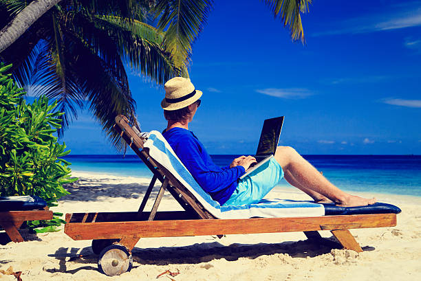 istock man with laptop on tropical beach 506553134