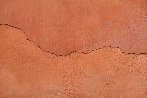 istock Old terracotta painted stucco wall with cracked plaster. Backgro 506554278
