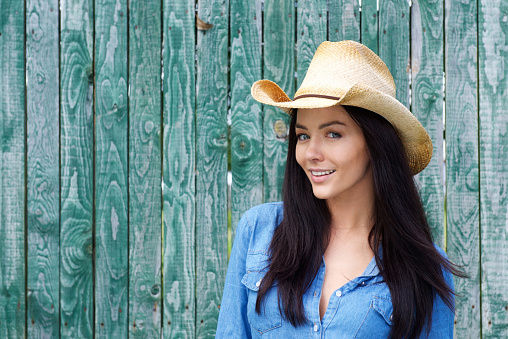 Close up portrait of a smiling young woman wearing cowboy hat
